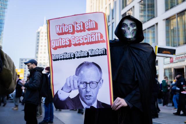 05 March 2026, Berlin: A participant wearing a skull mask holds a sign reading "War is good business. Invest your children!" during a demonstration, as part of a nationwide school strike against compulsory military service. Photo: Christoph Soeder/dpa