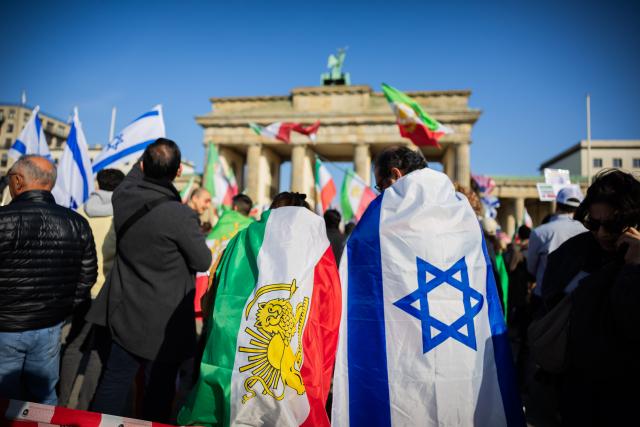07 March 2026, Berlin: People with the old Iranian flag and the Israeli flag take part in a protest celebrating the killing of Iran's Supreme Leader Ali Khamenei, at the Brandenburg Gate in Berlin. Photo: Christoph Soeder/dpa