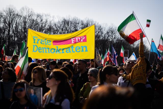 07 March 2026, Berlin: An FDP banner is seen during a protest celebrating the killing of Iran's Supreme Leader Ali Khamenei, at the Brandenburg Gate in Berlin. Photo: Christoph Soeder/dpa