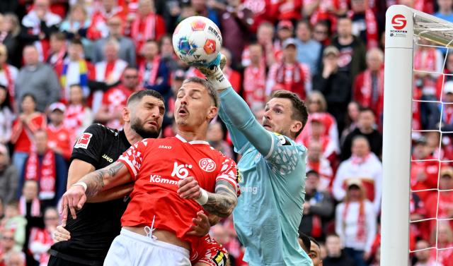 07 March 2026, Rhineland-Palatinate, Mainz: Mainz' goalkeeper Daniel Batz clears the ball in front of Stuttgart's Ameen Al-Dakhil (L) and Mainz' Philipp Tietz during the German Bundesliga soccer match between FSV Mainz 05 and VfB Stuttgart at the Mewa Arena. Photo: Torsten Silz/dpa - IMPORTANT NOTICE: DFL and DFB regulations prohibit any use of photographs as image sequences and/or quasi-video.