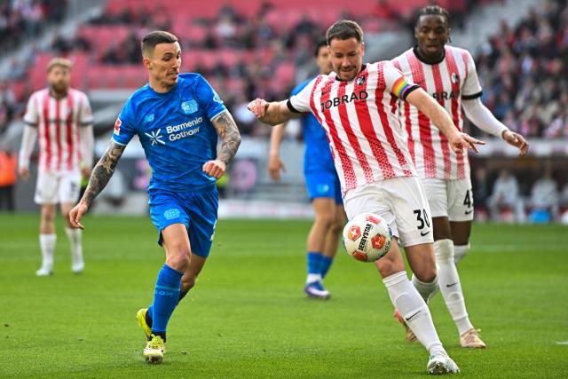 07 March 2026, Freiburg Im Breisgau: Bayer Leverkusen's Alex Grimaldo and Freiburg's Christian Guenter battle for the ball during the German Bundesliga soccer match between SC Freiburg and Bayer Leverkusen at the Europa-Park Stadium. Photo: Achim Keller/dpa - IMPORTANT NOTICE: DFL and DFB regulations prohibit any use of photographs as image sequences and/or quasi-video.
