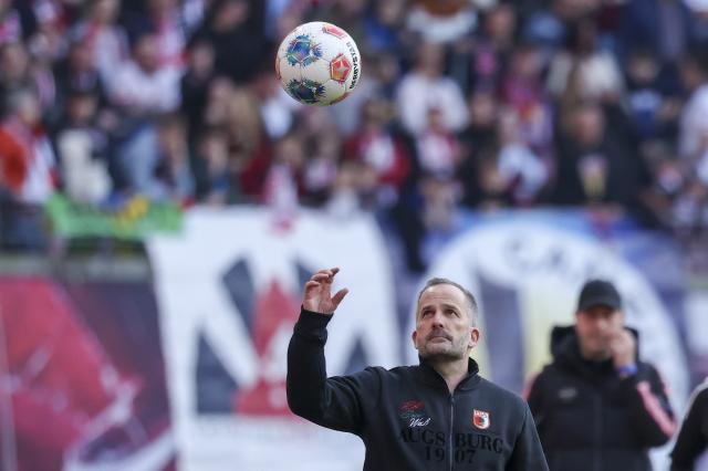 07 March 2026, Saxony, Leipzig: Augsburg coach Manuel Baum catches a ball during the German Bundesliga soccer match between RB Leipzig and FC Augsburg at the Red Bull Arena. Photo: Jan Woitas/dpa - IMPORTANT NOTICE: DFL and DFB regulations prohibit any use of photographs as image sequences and/or quasi-video.