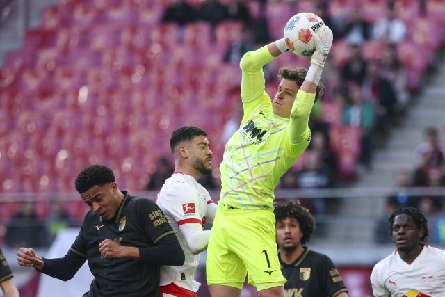 07 March 2026, Saxony, Leipzig: Augsburg goalkeeper Finn Dahmen clears the ball from Leipzig's Romulo Cardoso during the German Bundesliga soccer match between RB Leipzig and FC Augsburg at the Red Bull Arena. Photo: Jan Woitas/dpa - IMPORTANT NOTICE: DFL and DFB regulations prohibit any use of photographs as image sequences and/or quasi-video.