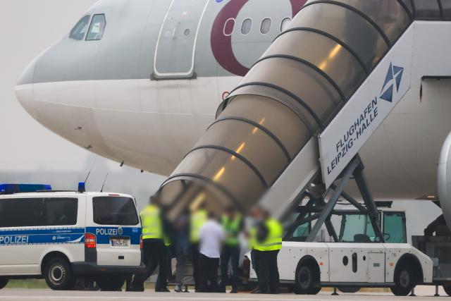 FILED - 18 July 2025, Sachsen, Schkeuditz: People board a Qatar Airways plane in front of federal police vehicles on the apron at Leipzig/Halle Airport. Germany failed to carry out 60% of planned deportations last year, according to recent figures that prompted calls for tougher measures by conservative lawmakers. Photo: Jan Woitas/dpa - ACHTUNG: Person(en) wurde(n) aus rechtlichen Gründen gepixelt