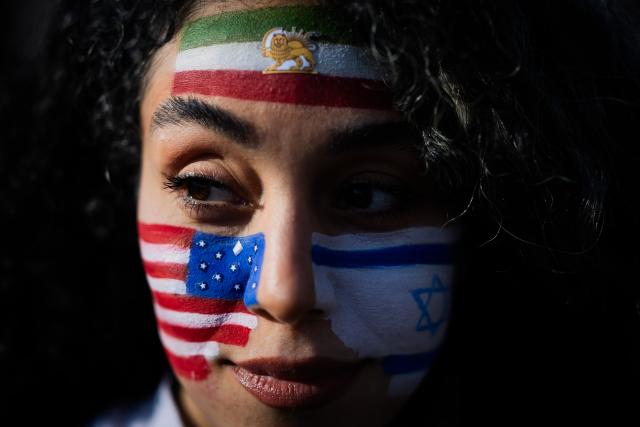 07 March 2026, Berlin: Mozhgan, with the flags of the US, Israel and Iran painted on their face takes part in a protest celebrating the killing of Iran's Supreme Leader Ali Khamenei, at the Brandenburg Gate in Berlin. Photo: Christoph Soeder/dpa