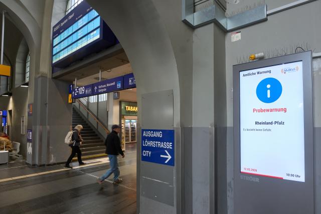 12 March 2026, Rheinland-Pfalz: Warnings are displayed on a promotional screen at Koblenz Central Station during the state-wide warning day, as the state of Rhineland-Palatinate conducts its emergency rehearsal, sending out a test alarm across the state via its emergency warning systems. Photo: Thomas Frey/dpa