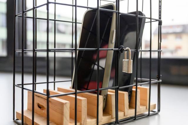 FILED - 13 February 2026, Lower Saxony, Northeim: Two smartphones are symbolically placed in a metal cage. The secondary school in Northeim introduced special cages in the second semester to reduce the use of cell phones in class. Photo: Swen Pförtner/dpa