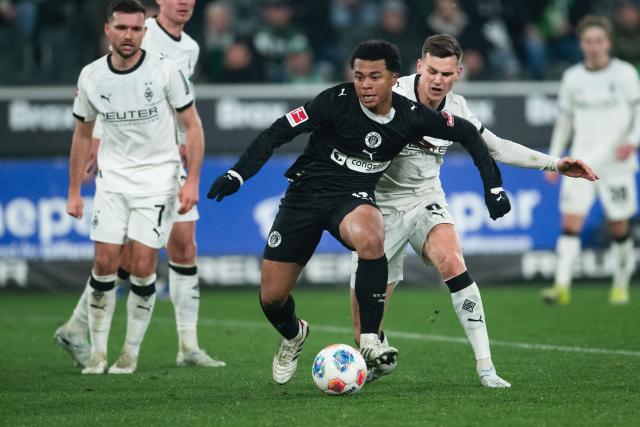 13 March 2026, North Rhine-Westphalia, Moenchengladbach: Gladbach's Yannik Engelhardt and Pauli's Joel Chima Fujita battle for the ball during the German Bundesliga soccer match between Borussia Moenchengladbach and FC St. Pauli at the Borussia-Park Stadium. Photo: Marius Becker/dpa - IMPORTANT NOTICE: DFL and DFB regulations prohibit any use of photographs as image sequences and/or quasi-video.