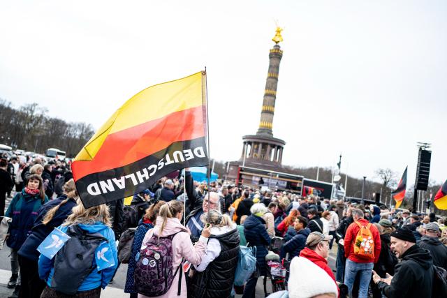 14 March 2026, Berlin: Participants at the "Transparency, Rule of Law, and Protection of Minors" demonstration hold an upside-down German flag while calling for "an investigation into possible German connections to the international Epstein scandal." Photo: Fabian Sommer/dpa