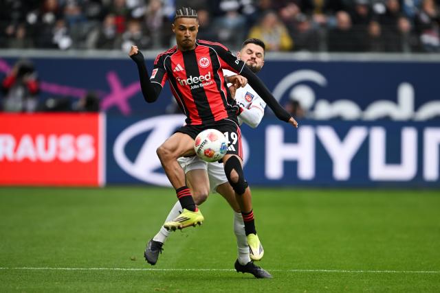 14 March 2026, Hesse, Frankfurt/M.: Frankfurt's Jean-Matteo Bahoya (L) and Heidenheim's Marnon Busch battle for the ball during the German Bundesliga soccer match between Eintracht Frankfurt and 1. FC Heidenheim at Deutsche Bank Park. Photo: Florian Wiegand/dpa - IMPORTANT NOTICE: DFL and DFB regulations prohibit any use of photographs as image sequences and/or quasi-video.