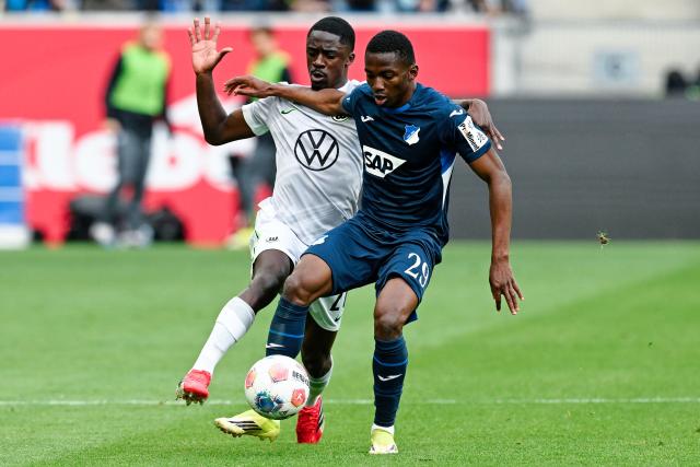 14 March 2026, Baden-Württemberg, Sinsheim: Wolfsburg's Sael Kumbedi and Hoffenheim's Bazoumana Toure battle for the ball during the German Bundesliga soccer match between TSG 1899 Hoffenheim and VfL Wolfsburg at the PreZero Arena. Photo: Uwe Anspach/dpa - IMPORTANT NOTICE: DFL and DFB regulations prohibit any use of photographs as image sequences and/or quasi-video.