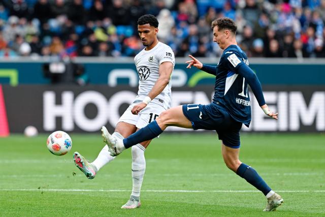 14 March 2026, Baden-Württemberg, Sinsheim: Wolfsburg's Moritz Jenz and Hoffenheim's Fisnik Asllani battle for the ball during the German Bundesliga soccer match between TSG 1899 Hoffenheim and VfL Wolfsburg at the PreZero Arena. Photo: Uwe Anspach/dpa - IMPORTANT NOTICE: DFL and DFB regulations prohibit any use of photographs as image sequences and/or quasi-video.