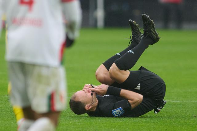 14 March 2026, North Rhine-Westphalia, Dortmund: Referee Bastian Dankert lies on the pitch after a collision during the German Bundesliga soccer match between Borussia Dortmund and FC Augsburg at Signal Iduna Park. Photo: Bernd Thissen/dpa - IMPORTANT NOTICE: DFL and DFB regulations prohibit any use of photographs as image sequences and/or quasi-video.