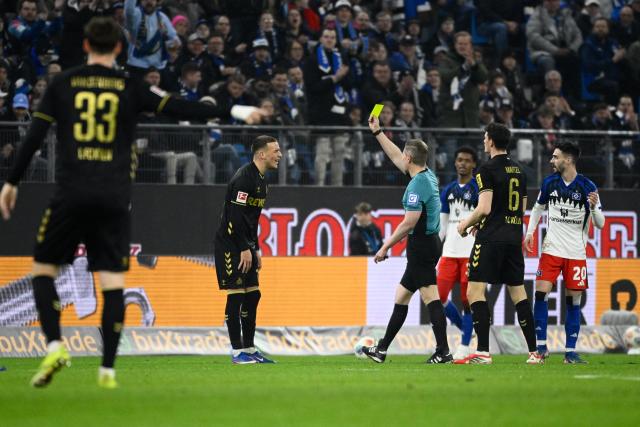 14 March 2026, Hamburg: Cologne's Said El Mala is booked by referee Tobias Welz for a foul during the German Bundesliga soccer match between Hamburger SV and 1. FC Cologne at the Volksparkstadion. Photo: Gregor Fischer/dpa - IMPORTANT NOTICE: DFL and DFB regulations prohibit any use of photographs as image sequences and/or quasi-video.