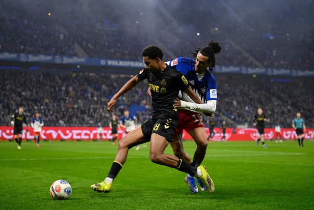 14 March 2026, Hamburg: Cologne's Youssoupha Niang and Hamburger's Damion Downs battle for the ball during the German Bundesliga soccer match between Hamburger SV and 1. FC Cologne at the Volksparkstadion. Photo: Gregor Fischer/dpa - IMPORTANT NOTICE: DFL and DFB regulations prohibit any use of photographs as image sequences and/or quasi-video.