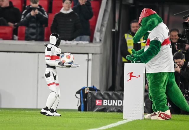 15 March 2026, Baden-Wuerttemberg, Stuttgart: A robot hands the match ball to Stuttgart's mascot, Fritzle before the German Bundesliga soccer match between VfB Stuttgart and RB Leipzig at MHPArena. Photo: Harry Langer/dpa - WICHTIGER HINWEIS: Gemäß den Vorgaben der DFL Deutsche Fußball Liga bzw. des DFB Deutscher Fußball-Bund ist es untersagt, in dem Stadion und/oder vom Spiel angefertigte Fotoaufnahmen in Form von Sequenzbildern und/oder videoähnlichen Fotostrecken zu verwerten bzw. verwerten zu lassen.