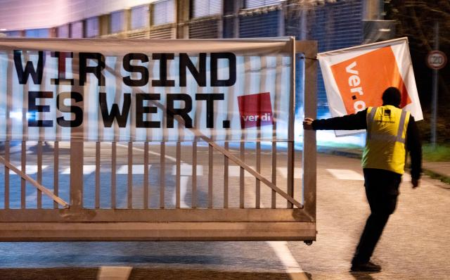 17 March 2026, North Rhine-Westphalia, Bonn: Verdi union flags and banners decorate the entrance to the Bonn Public Utilities depot as workers hold a picket line and close the gate during a warning strike. Photo: Benjamin Westhoff/dpa