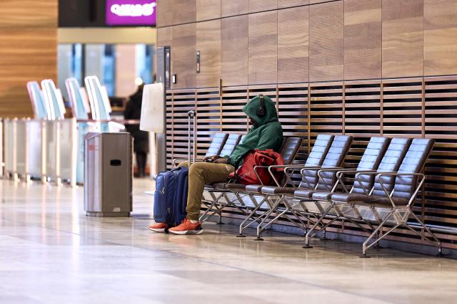18 March 2026, Brandenburg, Schoenefeld: A lone traveler sits on a bench in Terminal 1 at Berlin Brandenburg Airport (BER), waiting. Due to a warning strike by the Verdi union, no passenger flights take off or land at BER, with all departures and arrivals canceled for the entire day, as previously announced by the airport operator. Photo: Michael Ukas/dpa
