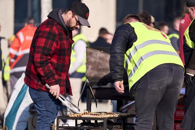 18 March 2026, Brandenburg, Schoenefeld: Striking airport employees and Verdi union members stand in front of the terminal during a warning strike at Berlin Brandenburg Airport (BER), halting all operations. No passenger flights have taken off or landed at BER since this morning, with all departures and arrivals cancelled for the entire day, the Berlin-Brandenburg Airport Company (FBB) had announced. Photo: Michael Ukas/dpa