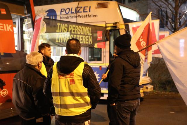19 March 2026, North Rhine-Westphalia, Cologne: Strikers stand with flags in front of parked trams during a warning strike. As part of ongoing collective bargaining negotiations for local public transportation, the Verdi union has called for warning strikes to take place simultaneously in several states on Thursday. Photo: Sascha Thelen/dpa