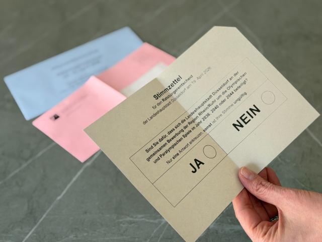 19 March 2026, North Rhine-Westphalia, Duesseldorf: A man holds ballot papers for the referendum on the Rhine-Ruhr region's Olympic bid. The voting documents have been sent out for some time. Photo: Oliver Auster/dpa