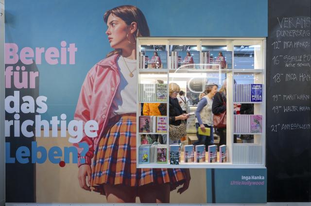 19 March 2026, Saxony, Leipzig: Visitors can be seen through a display window of a stand at the Leipzig Book Fair. From March 19 to March 22, 2026, exhibitors from over 50 countries will be presenting new book releases. The motto of this year's fair is "Where stories connect us". Photo: Jan Woitas/dpa