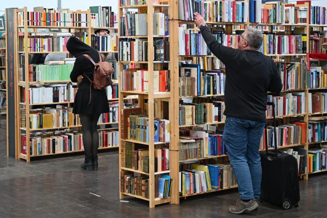 19 March 2026, Saxony, Leipzig: Visitors stand at bookshelves at the Leipzig Book Fair. From March 19 to March 22, 2026, exhibitors from over 50 countries will be presenting new book releases. The motto of this year's fair is "Where stories connect us". Photo: David Hammersen/dpa