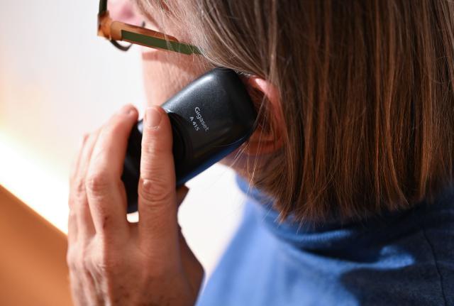 ILLUSTRATION - 07 November 2025, Stuttgart: A woman holds a landline phone to her ear. A 21-year-old German man who realized he had been targeted by a fraud call resorted to unusual means to help bust the scammers. Photo: Bernd Weißbrod/dpa