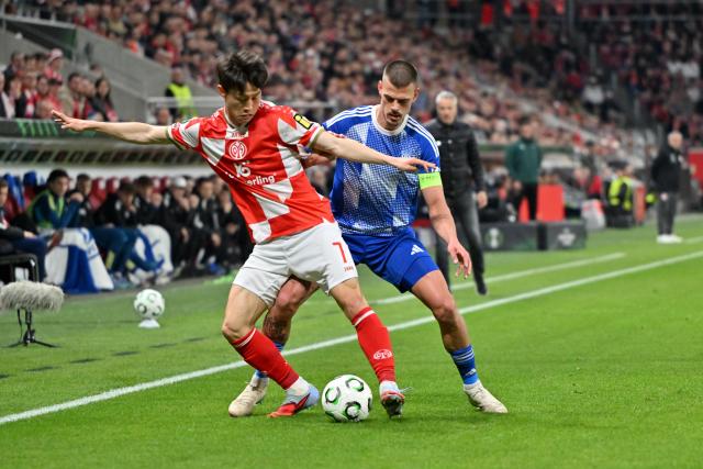 19 March 2026, Rheinland-Pfalz, Mainz: Mainz's Jae-sung Lee (L) and Sigma Olomouc's Jan Kliment battle for the ball during the UEFA Europa Conference League round of 16 second leg soccer match between FSV Mainz 05 and Sigma Olomouc at Mewa Arena. Photo: Torsten Silz/dpa