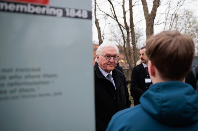 21 March 2026, Berlin: Accompanied by pupils from the Georg-Herwegh-Gymnasium Berlin, Federal President Frank-Walter Steinmeier stands in front of one of five stations that tell of the events of the Berlin March Uprising. The cemetery of those who died in the March Uprising is one of more than 250 sites that collectively commemorate the history of German democracy. Photo: Carsten Koall/dpa