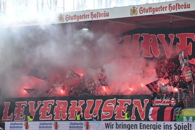 21 March 2026, Baden-Wuerttemberg, Heidenheim: Leverkusen fans set off pyrotechnics during the German Bundesliga soccer match between 1. FC Heidenheim and Bayer Leverkusen at Voith-Arena. Photo: Harry Langer/dpa - WICHTIGER HINWEIS: Gemäß den Vorgaben der DFL Deutsche Fußball Liga bzw. des DFB Deutscher Fußball-Bund ist es untersagt, in dem Stadion und/oder vom Spiel angefertigte Fotoaufnahmen in Form von Sequenzbildern und/oder videoähnlichen Fotostrecken zu verwerten bzw. verwerten zu lassen.