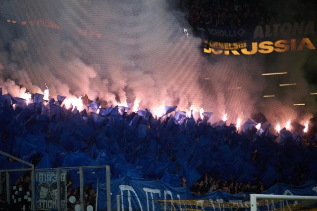 21 March 2026, North Rhine-Westphalia, Dortmund: Hamburger SV fans set off pyrotechnics during the German Bundesliga soccer match between Borussia Dortmund and Hamburger SV at Signal Iduna Park. Photo: Bernd Thissen/dpa - WICHTIGER HINWEIS: Gemäß den Vorgaben der DFL Deutsche Fußball Liga bzw. des DFB Deutscher Fußball-Bund ist es untersagt, in dem Stadion und/oder vom Spiel angefertigte Fotoaufnahmen in Form von Sequenzbildern und/oder videoähnlichen Fotostrecken zu verwerten bzw. verwerten zu lassen.