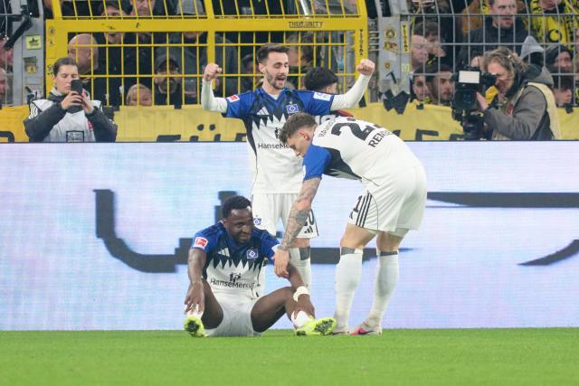 21 March 2026, North Rhine-Westphalia, Dortmund: Hamburger's Philip Otele (L) celebrates scoring his side's first goal with teammates Fabio Vieira (C) and Nicolai Remberg during the German Bundesliga soccer match between Borussia Dortmund and Hamburger SV at Signal Iduna Park. Photo: Bernd Thissen/dpa - WICHTIGER HINWEIS: Gemäß den Vorgaben der DFL Deutsche Fußball Liga bzw. des DFB Deutscher Fußball-Bund ist es untersagt, in dem Stadion und/oder vom Spiel angefertigte Fotoaufnahmen in Form von Sequenzbildern und/oder videoähnlichen Fotostrecken zu verwerten bzw. verwerten zu lassen.
