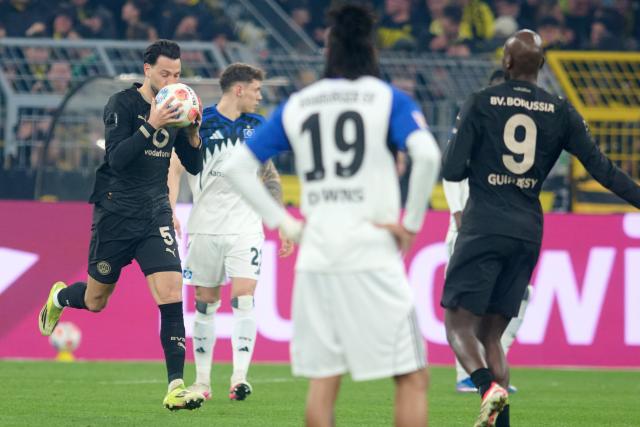 21 March 2026, North Rhine-Westphalia, Dortmund: Borussia Dortmund's Ramy Bensebaini (L) celebrates scoring his side's first goal during the German Bundesliga soccer match between Borussia Dortmund and Hamburger SV at Signal Iduna Park. Photo: Bernd Thissen/dpa - WICHTIGER HINWEIS: Gemäß den Vorgaben der DFL Deutsche Fußball Liga bzw. des DFB Deutscher Fußball-Bund ist es untersagt, in dem Stadion und/oder vom Spiel angefertigte Fotoaufnahmen in Form von Sequenzbildern und/oder videoähnlichen Fotostrecken zu verwerten bzw. verwerten zu lassen.