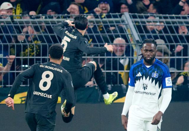 21 March 2026, North Rhine-Westphalia, Dortmund: Borussia Dortmund's Ramy Bensebaini (C) celebrates scoring his side's third goal during the German Bundesliga soccer match between Borussia Dortmund and Hamburger SV at Signal Iduna Park. Photo: Bernd Thissen/dpa - WICHTIGER HINWEIS: Gemäß den Vorgaben der DFL Deutsche Fußball Liga bzw. des DFB Deutscher Fußball-Bund ist es untersagt, in dem Stadion und/oder vom Spiel angefertigte Fotoaufnahmen in Form von Sequenzbildern und/oder videoähnlichen Fotostrecken zu verwerten bzw. verwerten zu lassen.