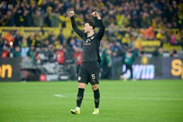 21 March 2026, North Rhine-Westphalia, Dortmund: Borussia Dortmund's Ramy Bensebaini celebrates after the German Bundesliga soccer match between Borussia Dortmund and Hamburger SV at Signal Iduna Park. Photo: Bernd Thissen/dpa - WICHTIGER HINWEIS: Gemäß den Vorgaben der DFL Deutsche Fußball Liga bzw. des DFB Deutscher Fußball-Bund ist es untersagt, in dem Stadion und/oder vom Spiel angefertigte Fotoaufnahmen in Form von Sequenzbildern und/oder videoähnlichen Fotostrecken zu verwerten bzw. verwerten zu lassen.