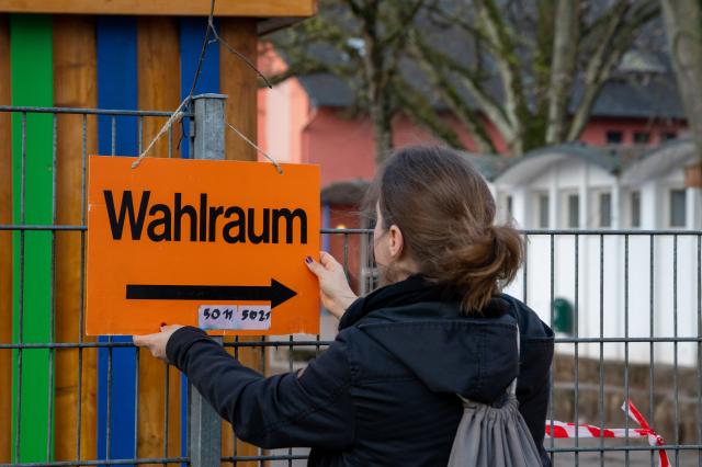 22 March 2026, Rhineland-Palatinate, Koblenz: Election assessor Simone Streit attaches a sign to the polling station in the morning. Photo: Harald Tittel/dpa