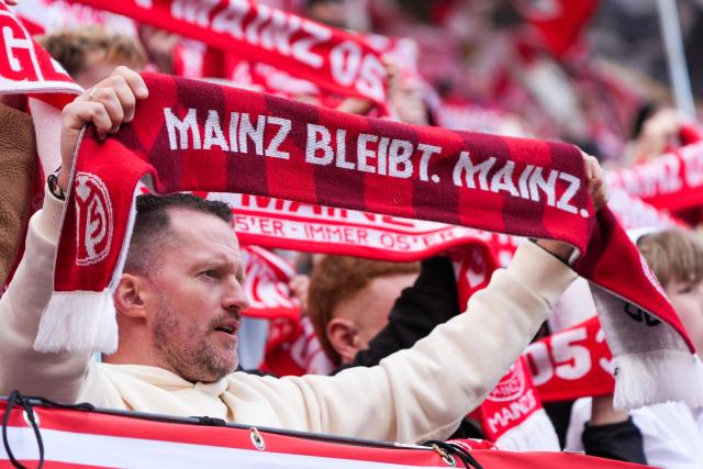 22 March 2026, Rhineland-Palatinate, Mainz: Mainz fans wave their scarves, some of which bear the slogan 'Mainz stays. Mainz' ahead of the German Bundesliga soccer match between FSV Mainz 05 and Eintracht Frankfurt at the Mewa Arena. Photo: Marc Schüler/dpa - IMPORTANT NOTICE: DFL and DFB regulations prohibit any use of photographs as image sequences and/or quasi-video.