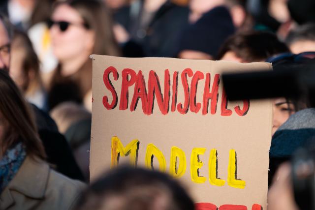 22 March 2026, Berlin: A sign reading "Spanish Model" is seen during a demonstration against sexualized digital violence in front of the Brandenburg Gate. Photo: Carsten Koall/dpa