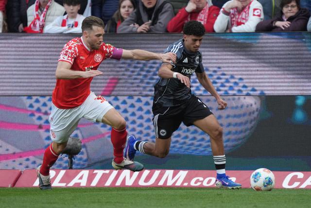 22 March 2026, Rhineland-Palatinate, Mainz: Eintracht Frankfurt's Ayoube Amaimouni-Echghouyab (R) Mainz's beats Silvan Widmer (L) battle for the ball during the German Bundesliga soccer match between FSV Mainz 05 and Eintracht Frankfurt at the Mewa Arena. Photo: Marc Schüler/dpa - IMPORTANT NOTICE: DFL and DFB regulations prohibit any use of photographs as image sequences and/or quasi-video.