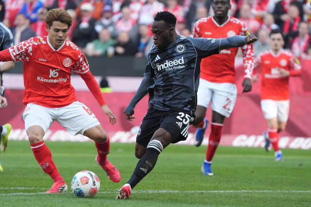 22 March 2026, Rhineland-Palatinate, Mainz: Eintracht Frankfurt's Arnaud Kalimuendo takes a shot against Mainz's Kaishu Sano (L) during the German Bundesliga soccer match between FSV Mainz 05 and Eintracht Frankfurt at the Mewa Arena. Photo: Marc Schüler/dpa - IMPORTANT NOTICE: DFL and DFB regulations prohibit any use of photographs as image sequences and/or quasi-video.