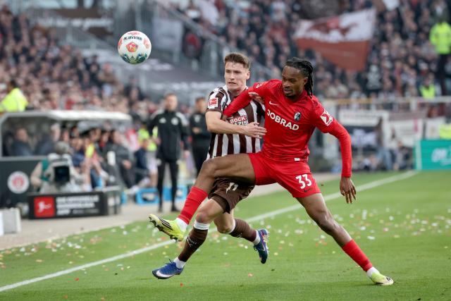 22 March 2026, Hamburg: St. Pauli's Arkadiusz Pyrka (L) and Freiburg's Jordi Makengo battle for the ball during the German Bundesliga soccer match between FC St. Pauli and SC Freiburg at the Millerntor Stadium. Photo: Christian Charisius/dpa - WICHTIGER HINWEIS: Gemäß den Vorgaben der DFL Deutsche Fußball Liga bzw. des DFB Deutscher Fußball-Bund ist es untersagt, in dem Stadion und/oder vom Spiel angefertigte Fotoaufnahmen in Form von Sequenzbildern und/oder videoähnlichen Fotostrecken zu verwerten bzw. verwerten zu lassen.