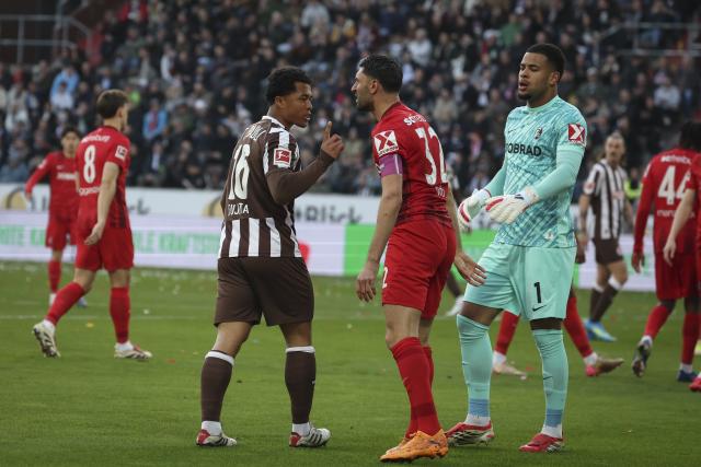 22 March 2026, Hamburg: St. Pauli's Joel Chima Fujita (L), Freiburg's Vincenzo Grifo and Freiburg goalkeeper Noha Atubolu (R) discuss the play during the German Bundesliga soccer match between FC St. Pauli and SC Freiburg at the Millerntor Stadium. Photo: Christian Charisius/dpa - WICHTIGER HINWEIS: Gemäß den Vorgaben der DFL Deutsche Fußball Liga bzw. des DFB Deutscher Fußball-Bund ist es untersagt, in dem Stadion und/oder vom Spiel angefertigte Fotoaufnahmen in Form von Sequenzbildern und/oder videoähnlichen Fotostrecken zu verwerten bzw. verwerten zu lassen.