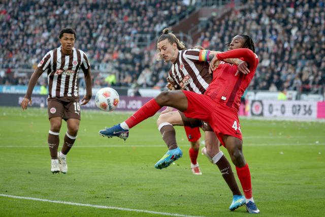 22 March 2026, Hamburg: St. Pauli's Jackson Irvine (L) and Freiburg's Johan Manzambi (R) battle for the ball during the German Bundesliga soccer match between FC St. Pauli and SC Freiburg at the Millerntor Stadium. Photo: Christian Charisius/dpa - WICHTIGER HINWEIS: Gemäß den Vorgaben der DFL Deutsche Fußball Liga bzw. des DFB Deutscher Fußball-Bund ist es untersagt, in dem Stadion und/oder vom Spiel angefertigte Fotoaufnahmen in Form von Sequenzbildern und/oder videoähnlichen Fotostrecken zu verwerten bzw. verwerten zu lassen.