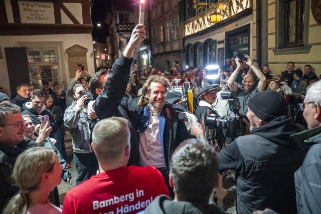 22 March 2026, Bavaria, Bamberg: Bamberg's new mayor, Sebastian Niedermaier (C), is welcomed in a ceremony in front of the Schlenkerla restaurant. On Sunday, the runoff election for mayor of Bamberg took place between J. Glüsenkamp (Alliance 90/The Greens) and Sebastian Niedermaier (SPD). Photo: Daniel Vogl/dpa