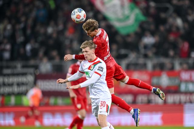 22 March 2026, Bavaria, Augsburg: Augsburg's Anton Kade (L) and Stuttgart's Maximilian Mittelstaedt battle for the ball during the German Bundesliga match between FC Augsburg and VfB Stuttgart at the Millerntor Stadium. Photo: Harry Langer/dpa - WICHTIGER HINWEIS: Gemäß den Vorgaben der DFL Deutsche Fußball Liga bzw. des DFB Deutscher Fußball-Bund ist es untersagt, in dem Stadion und/oder vom Spiel angefertigte Fotoaufnahmen in Form von Sequenzbildern und/oder videoähnlichen Fotostrecken zu verwerten bzw. verwerten zu lassen.