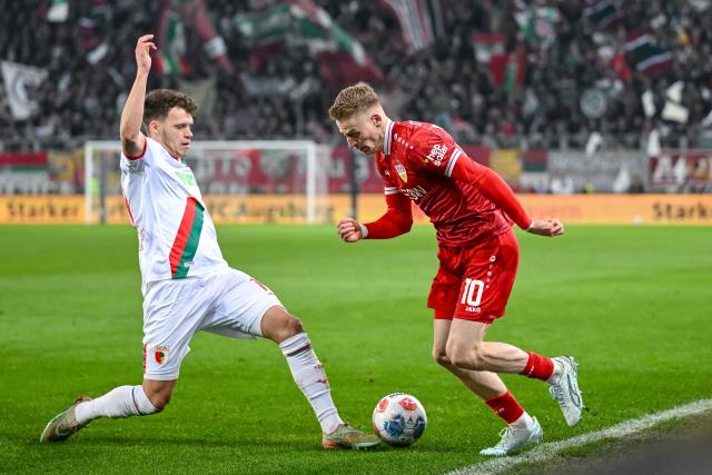 22 March 2026, Bavaria, Augsburg: Augsburg's Robin Fellhauer (L) and Stuttgart's Chris Fuehrich battle for the ball during the German Bundesliga match between FC Augsburg and VfB Stuttgart at the Millerntor Stadium. Photo: Harry Langer/dpa - WICHTIGER HINWEIS: Gemäß den Vorgaben der DFL Deutsche Fußball Liga bzw. des DFB Deutscher Fußball-Bund ist es untersagt, in dem Stadion und/oder vom Spiel angefertigte Fotoaufnahmen in Form von Sequenzbildern und/oder videoähnlichen Fotostrecken zu verwerten bzw. verwerten zu lassen.