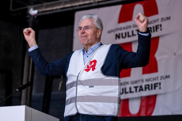 23 March 2026, Bavaria, Munich: Hans-Peter Hubmann, Chairman of the German Pharmacists' Association (DAV), clenches his fists on stage during a nationwide day of protest by pharmacies for higher pay.  Pharmacies are called upon to keep their stores closed on the day of protest by pharmacies for higher remuneration. Photo: Lennart Preiss/dpa