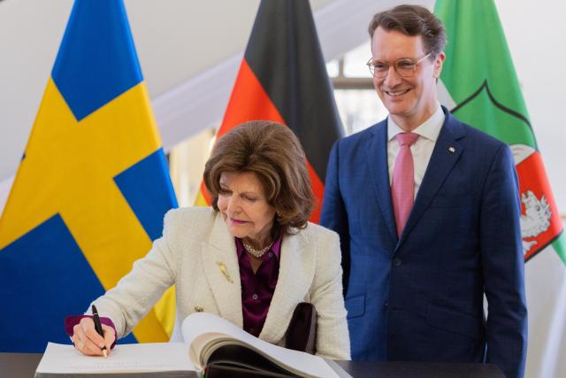 23 March 2026, North Rhine-Westphalia, Duesseldorf: Queen Silvia of Sweden signs the Golden Book in the State Chancellery alongside Hendrik Wuest, Minister President of North Rhine-Westphalia. Photo: Rolf Vennenbernd/dpa
