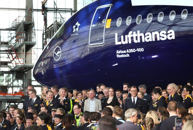 23 March 2026, Bavaria, Munich: Lufthansa employees stand in front of the Airbus A350-900 Rostock on the occasion of Lufthansa's 100th anniversary celebrations. Photo: Karl-Josef Hildenbrand/dpa